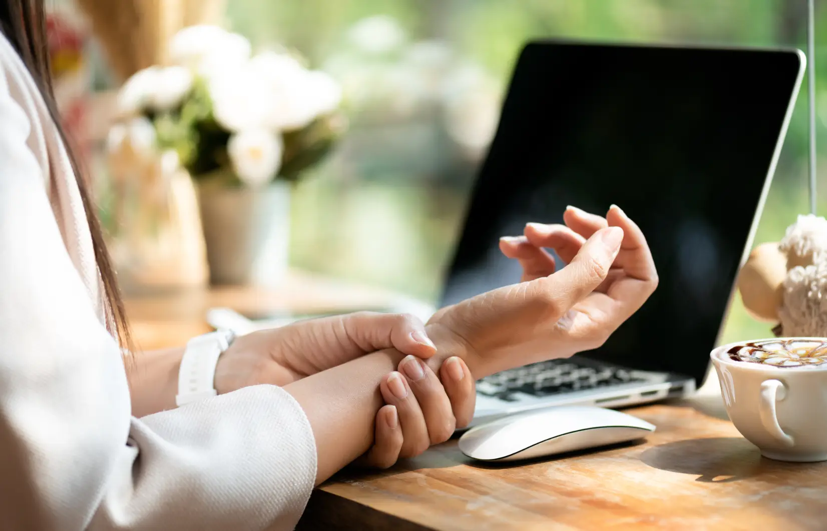 Ženska si drži zapestje ob bolečini po delu z računalnikom – znak pekoče bolečine zaradi sindroma karpalnega kanala.